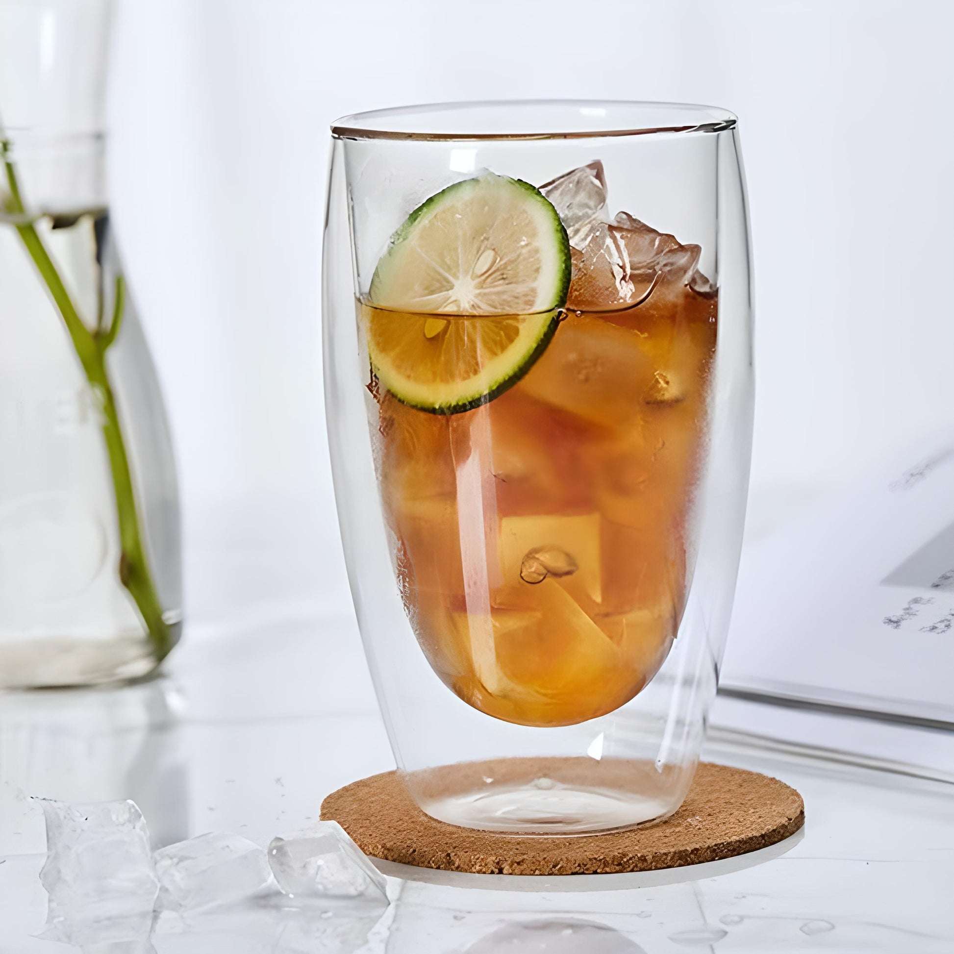 A single double wall glass with ice and fizzy drink in it
