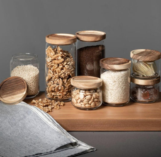 Various sizes of glass jars with acacia wood lids each containing different filling within them